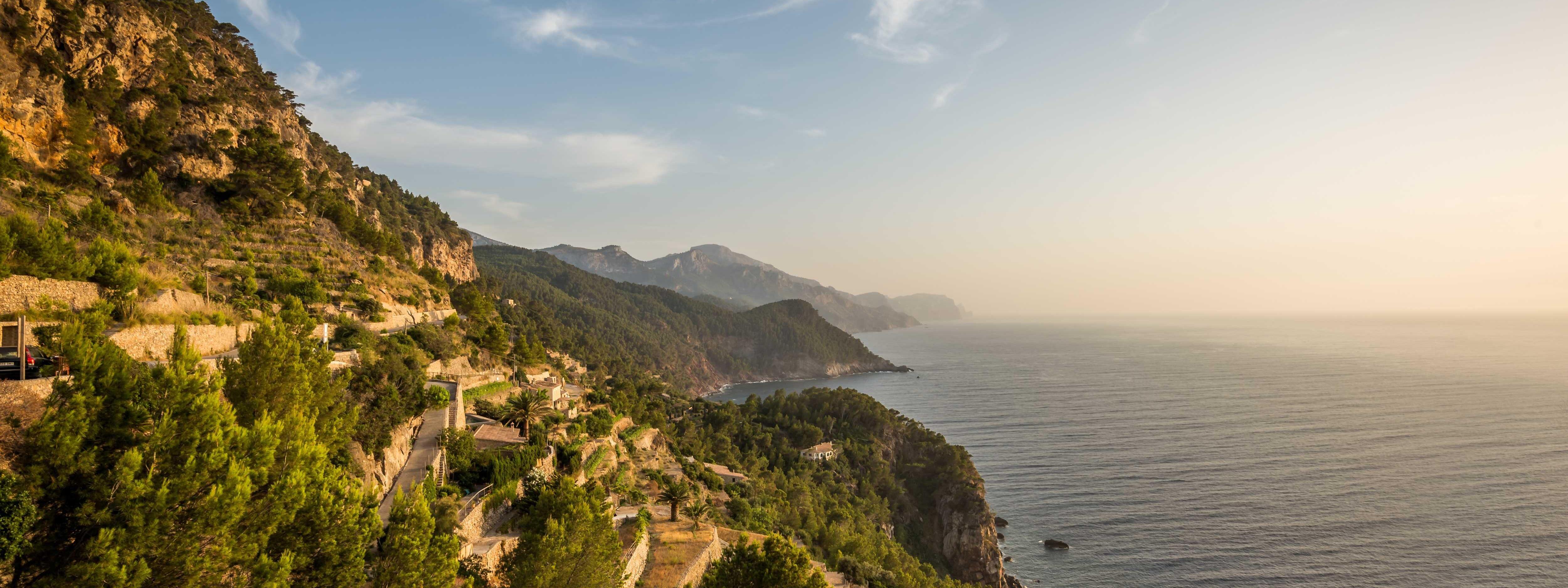 Küstenlandschaft mit Serpentinen an einem Steilhang, im sanften Licht der Abenddämmerung.